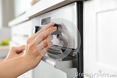 Woman regulating cooking mode on oven panel in kitchen Stock Photo