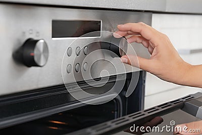 Woman regulating cooking mode on oven panel Stock Photo