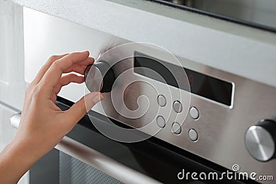 Woman regulating cooking mode on oven panel Stock Photo