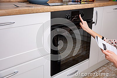 Woman regulating cooking mode on oven panel Stock Photo