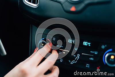 Woman regulating temperature on car air condition. Stock Photo