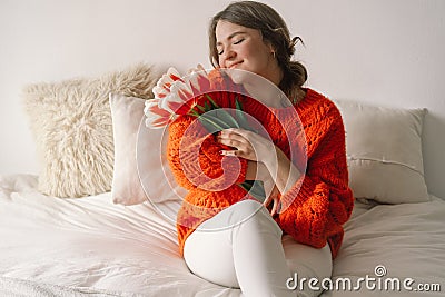 Woman rejoice at tulips. Beautiful woman sits on the bed Stock Photo