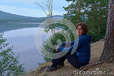 Woman relaxes on lakeshore in summer morning Stock Photo