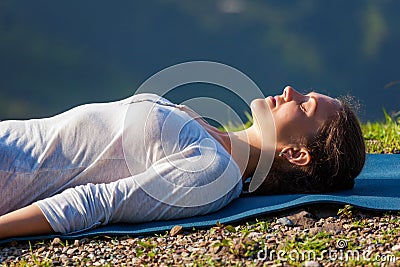 Woman relaxes in yoga asana Savasana outdoors Stock Photo