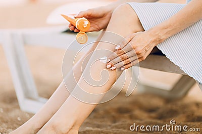 Woman is relaxing on the beach, lying on a sunbed, applying sunscreen to her feet . Summer holiday Stock Photo