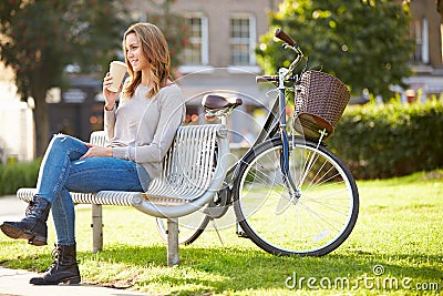 Woman Relaxing On Park Bench With Takeaway Coffee Stock Photo