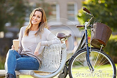 Woman Relaxing On Park Bench With Takeaway Coffee Stock Photo