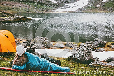 Woman relaxing in sleeping bag on mat enjoying lake Stock Photo