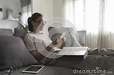Woman relaxing on the sofa and watching pictures in the photo album Stock Photo