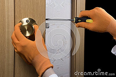 Woman repairing door handle close up. Women home service concept. Hand holding screwdriver. Stock Photo