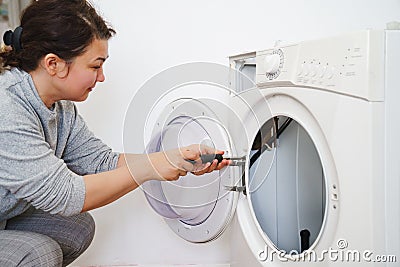 the woman repairs the washing machine, disassembles into parts Stock Photo