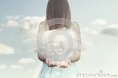 Woman resembling an angel guards a small cloud in her hands Stock Photo