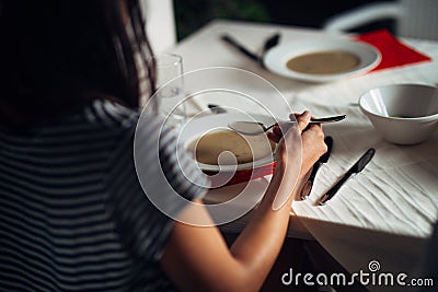 Woman in restaurant eating vegetarian vegan cream soup.Gluten free and diet food.Female eating bone broth based soup.Nutrition Stock Photo