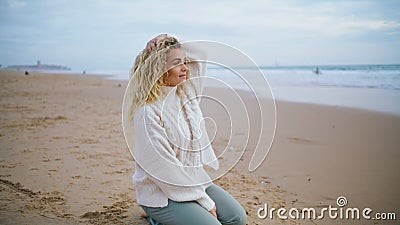 Woman resting autumn beach on cloudy day. Beautiful curly tourist looking camera Stock Photo