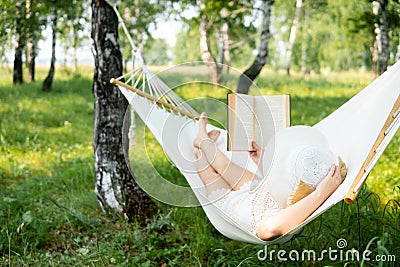 Woman resting in hammock outdoors. Relax and reading the book. Stock Photo