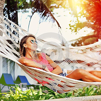 Woman is resting in the hammock under the palms on the tropical Stock Photo