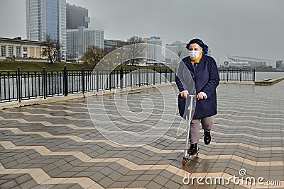 Woman rides a scooter with medical mask on face Stock Photo