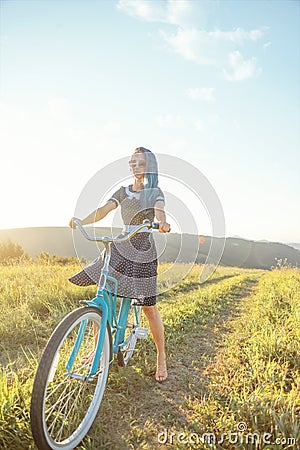 Woman riding bicycle cruiser on countryside path in summer. Stock Photo