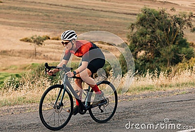 Woman riding a bicycle on empty road. Sportswoman in fitnesswear practicing on pro bike Stock Photo