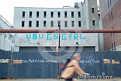 Woman riding a bicycle by a parking lot with street art signage Stock Photo