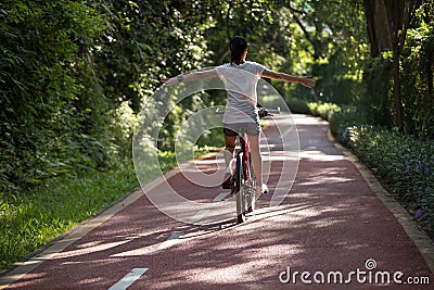 Woman riding a bike on sunny park trail Stock Photo