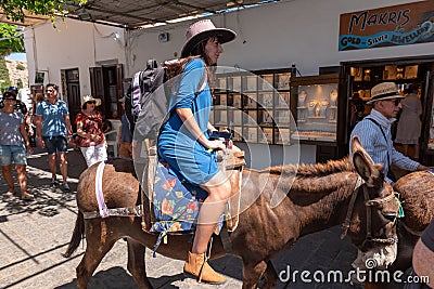Woman riding donkey. Using donkey taxi to the Acropolis is a popular tourist attraction in Lindos Editorial Stock Photo