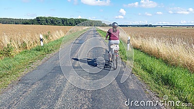 woman riding her bike on lonesome rural road Stock Photo