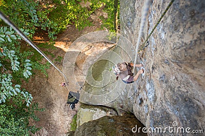 Woman rock climber is climbing on a rocky wall Stock Photo