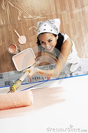 Woman With Roller Applying Pink Paint On A Wall Stock Photo