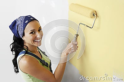 Woman With Roller Applying Yellow Paint On A Wall Stock Photo