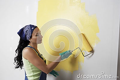 Woman With Roller Applying Yellow Paint On A Wall Stock Photo