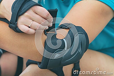 Woman rollerskater putting on elbow protector pads on her hand Stock Photo