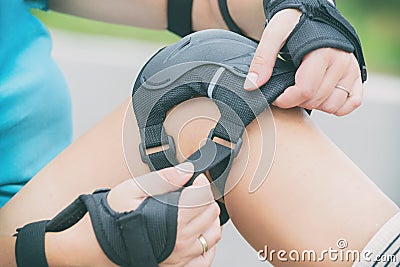 Woman rollerskater putting on knee protector pads Stock Photo