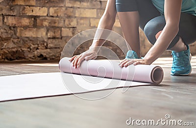 Woman rolling yoga pilates mat on gym studio floor, close up view Stock Photo