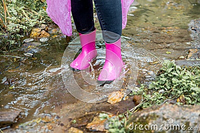 Woman in rubber boots and a raincoat walking in the rain Stock Photo