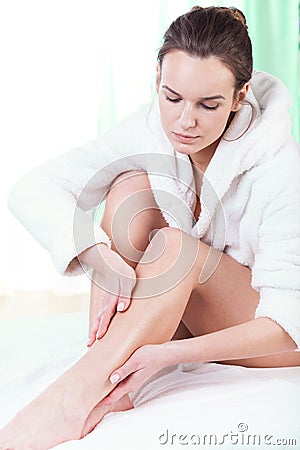 Woman rubbing lotion on her legs Stock Photo