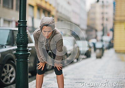 Woman runner in the rain taking a break and stretching Stock Photo