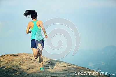 Woman runner running on mountain peak Stock Photo