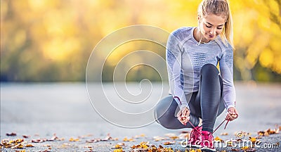 Woman runner tying shoelaces before jogging in autumn tree alley park. Sports female autumn outfit leggings and thermal underwear Stock Photo