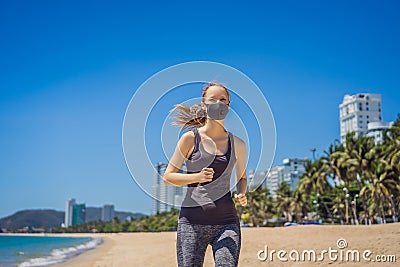 Woman runner wearing medical mask. Running in the city against the backdrop of the city. Coronavirus pandemic Covid-19 Stock Photo