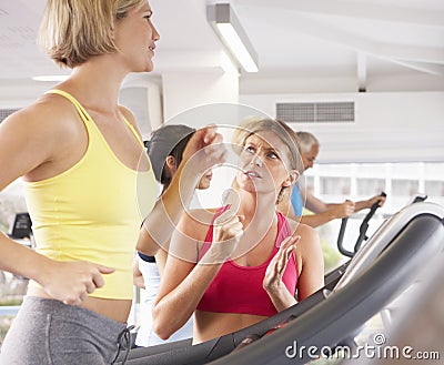 Woman On Running Machine In Gym Encouraged By Personal Trainer Stock Photo