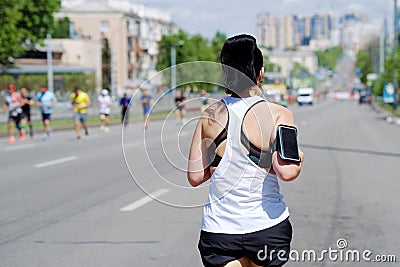Woman running with smartphone attached to shoulder Editorial Stock Photo