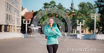 Woman running on a wide city street or bridge towards the camera with a smile Stock Photo