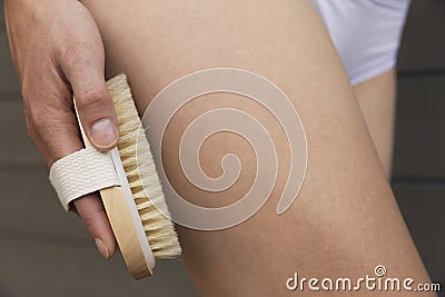 Woman`s arm holding dry brush to top of her leg. Cellulite treat Stock Photo