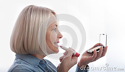 A woman's delicate hands and face in profile expertly adorning her face with makeup, as she prepares Stock Photo