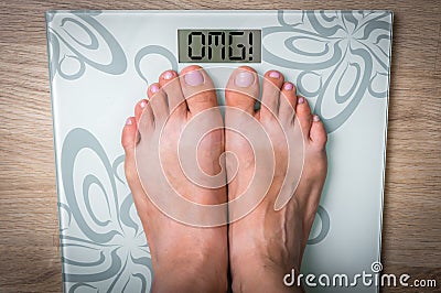 Woman's feet on a scale with word OMG! Stock Photo