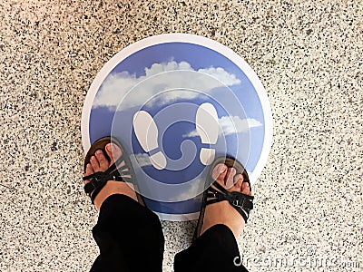 Woman`s feet on the sign on the floor of a supermarket to follow social distancing. Stock Photo