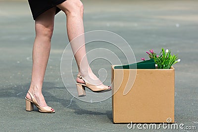 A woman`s foot kicks a box of personal belongings Stock Photo