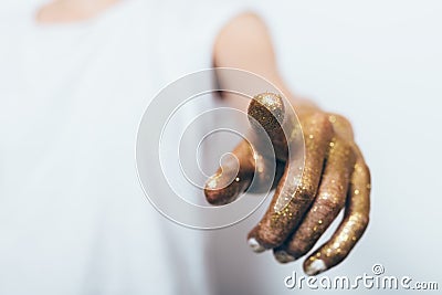 Woman`s hand covered with gold sequins pointing finger Stock Photo