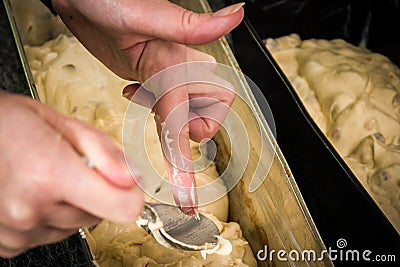 A woman`s hand and fingers scraping cake batter and dough from a Stock Photo